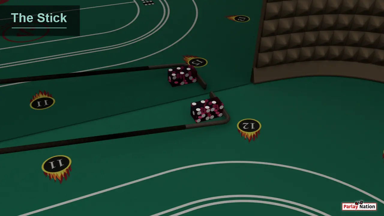 Two dice near spot twelve on the layout. The dice are being pulled back by a black stick and it's being reflected in the mirror.
